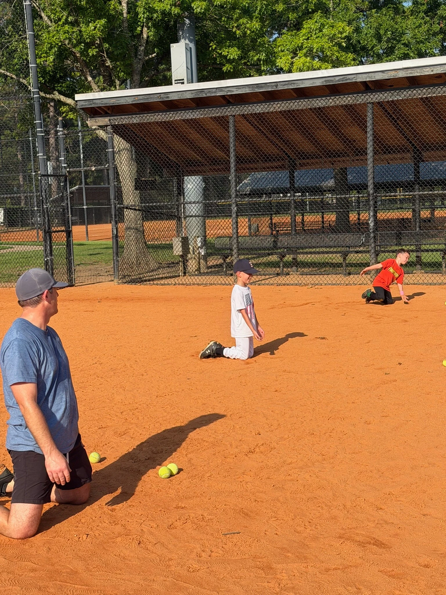 coach rolling grounders at fielding practice